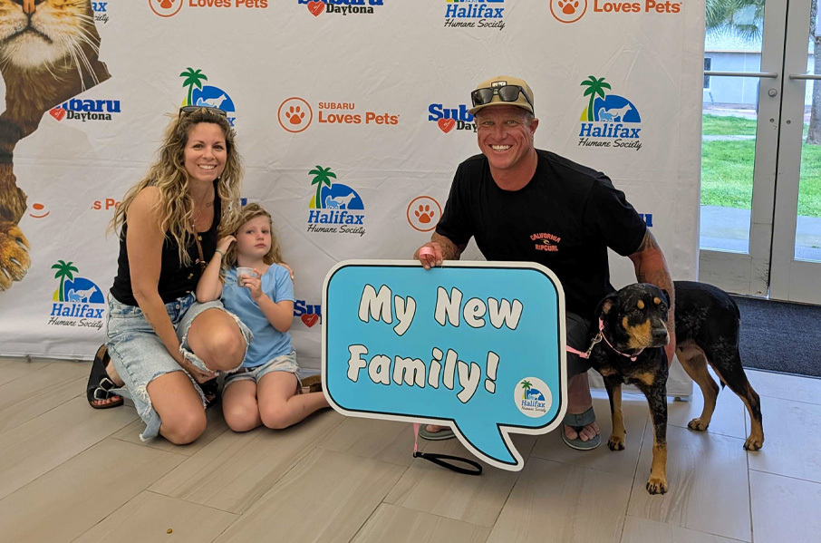 Dog adoption with a family and sign that says My New Family